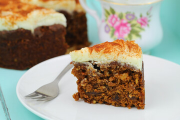 Slice of delicious carrot cake with walnuts and marzipan icing on white plate

