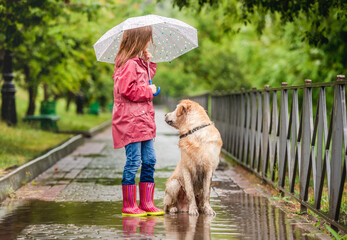 Little girl and dog walking under rain