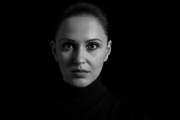 Beautiful woman in black stands in front of black background