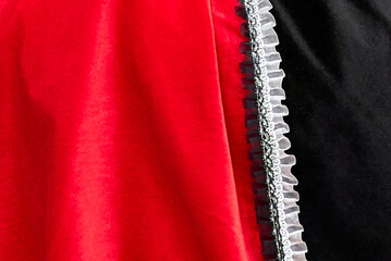 Close-up of a red and black colored fabric with attached white decorative rippled border