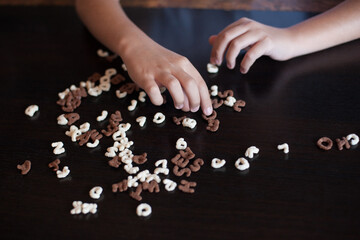the child collects words from edible letters on a dark background.