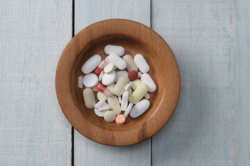 tablets and capsule in a wooden bowl.