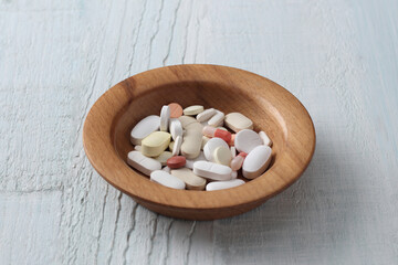 tablets and capsule in a wooden bowl.
