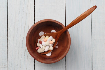 tablets and capsule in a wooden bowl.