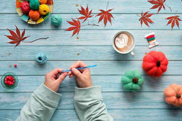 Woman hands kniting crochet. Top view of the wooden table with yarn balls, wool bundles, decorative...