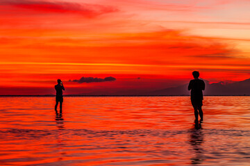Two people silhouetted taking photos of the beautiful sunset