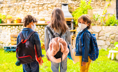 Three brother children with face masks ready for going back to school. New normality, social distance, coronavirus pandemic, covid-19. With all security measures