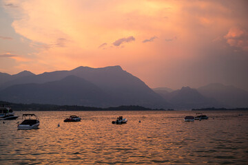 Amazing Red sunset with pink mist on Garda lake with still boats. Manerba del Garda, Lombardy, Italy.