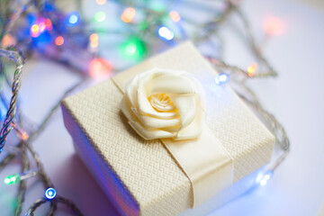 White gift box with bow and garland with red lights