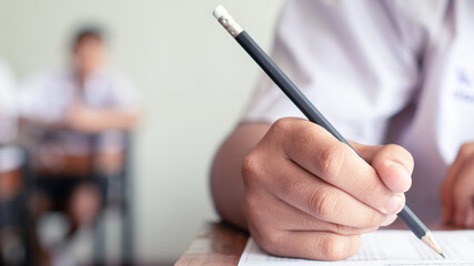 Hand of students writing and taking exam with stress in classroom.16:9 style