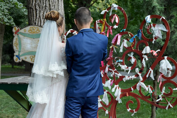 Newlyweds tie ribbons on a symbolic tree.