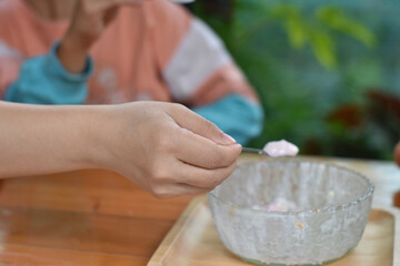 Close-up of hands holding spoon eating ice cream in cup. Selective focus