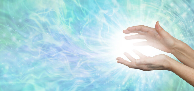 Faith Healers website banner background - female hands with bright white healing energy between against a wide blue green energy formation background with copy space
