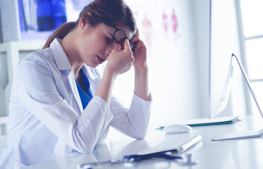 Portrait of a young female doctor suffering from a headache at work