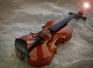Fototapeta na wymiar The wooden violin put on grunge surface background,Lens flare effect,blurry light around