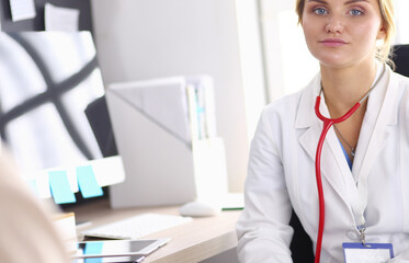 Portrait of young female doctor sitting at desk in hospital