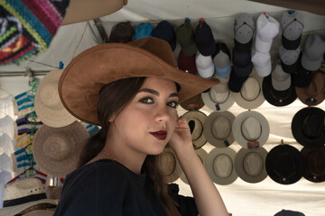 La joven se está probando un sombrero en un mercado de un pueblo.