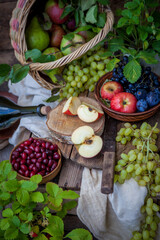 Autumn still life. Fruits and berries. Apples, grapes, strawberries, plums on a wooden table. Country style. Idle healthy vitamin food. Fruit harvest. Old knife. An apple in a basket.