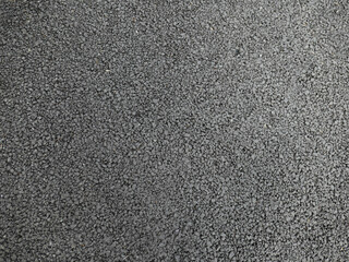 A smooth dark grey asphalt pavement texture with small rocks