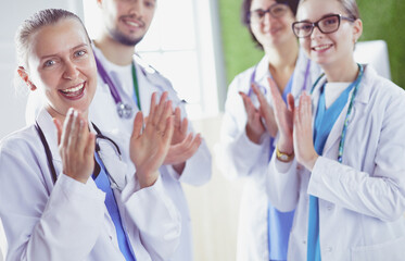 Fototapeta premium Happy medical team comprising male and female doctors smiling broadly and giving a thumbs up of success and hope