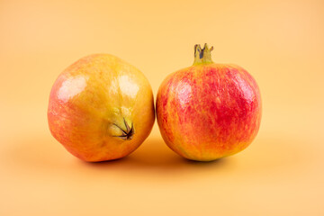 Two fresh pomegranate fruits on yellow background