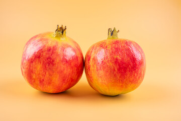 Two fresh pomegranate fruits on yellow background