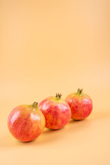 Three fresh pomegranate fruits on yellow background