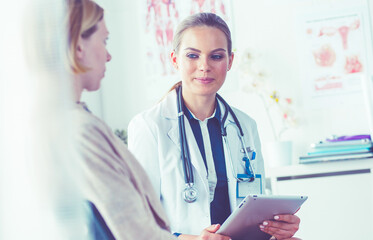 Doctor and patient discussing something while sitting at the table . Medicine and health care concept