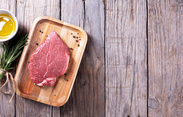 Beef steak with rosemary and pepper on a wooden background