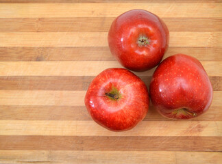 red apple sit on a worn butcher block cutting board