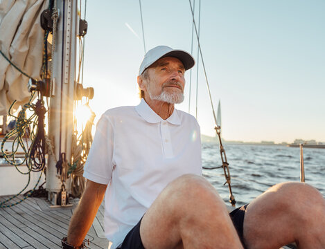 Portrait of a mature man sitting on his yacht. Senior captain enjoying a sunset on a sailboat.
