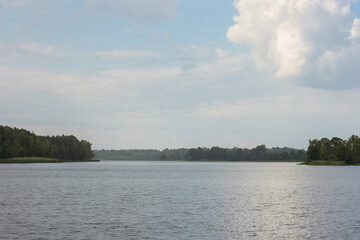 Rain on the lake on a sunny day. Reflection of clouds in the lake. Summer
