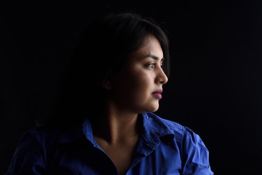 Side View Of Dark Portrait Of A Latin Woman On Black Background, Serious