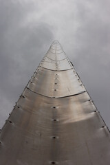 Flagpole lined with metal sheets on sky background. Bottom view