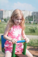 Fototapeta na wymiar Cute little kid girl portrait sit on city swing
