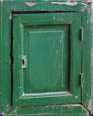 samall old wooden door with square frames of a box, painted in dark green color
