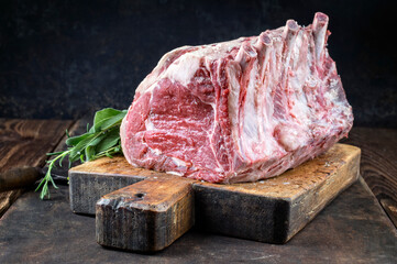 Raw dry aged angus cote de boeuf block offered as closeup on a rustic wooden cutting board