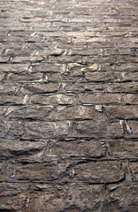 walk on the floor of an old town with gray stone tiles - vertical background in perspective of an ancient roman road in Europe