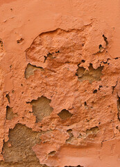 old orange wall with peeling painting - rough dirty texture for a background