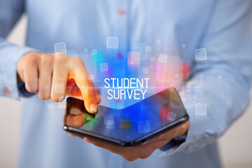 Young man holding a foldable smartphone with STUDENT SURVEY inscription, educational concept