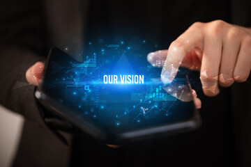 Businessman holding a foldable smartphone with OUR VISION inscription, business concept