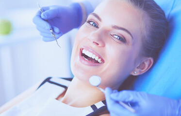 Young Female patient with open mouth examining dental inspection at dentist office.