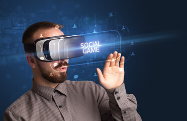 Businessman looking through Virtual Reality glasses with SOCIAL GAME inscription, social networking concept