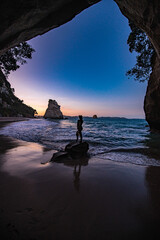 silhouette of a woman standing on a rock on the beach
