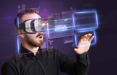 Businessman looking through Virtual Reality glasses with VIRTUAL MACHINE inscription, new technology concept