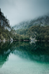 Panorama view of a crystal clear turquoise mountain lake on a moody rainy hiking outdoor day with mountains in the background. Gosauseen, Gosau, Austrian Alps, Salzkammergut in Austria, Europe
