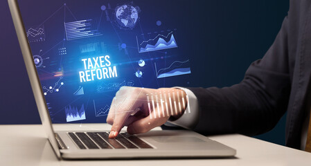 Businessman working on laptop with TAXES REFORM inscription, new business concept