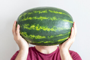 Man with watermelon hiding his face. How to pick a watermelon concept.