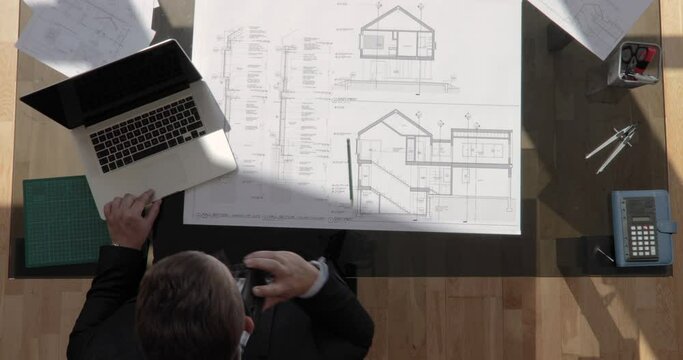 Zoom out top view shot of an architect is on the phone and working with floating sun shot in 4k