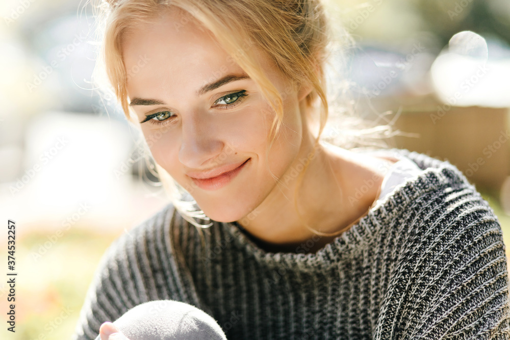 Wall mural green-eyed young woman in knitted sweater with charming smile is posing for close-up portrait